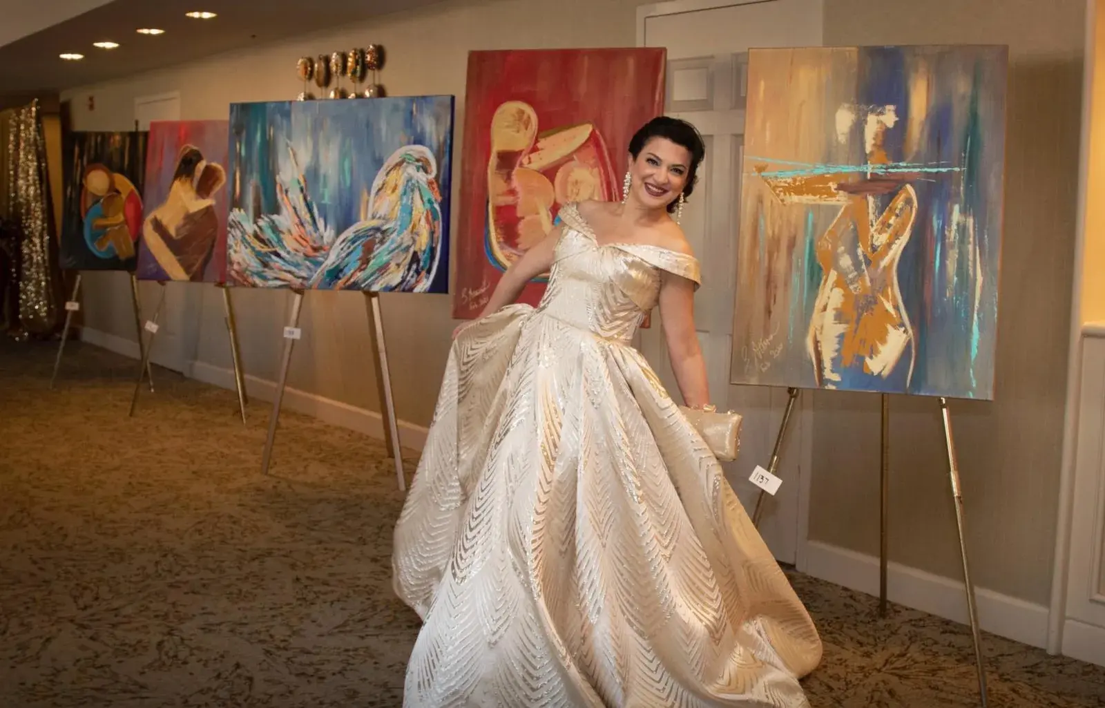 Saina Attaran standing among her paintings at an exhibition.